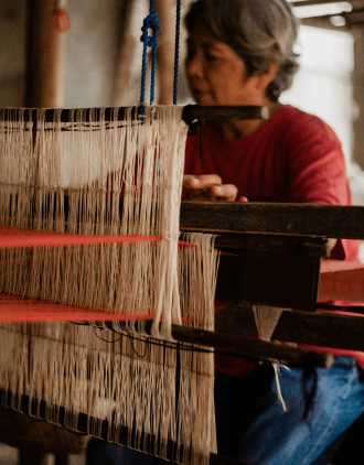 Artisan working at loom with yarn spools in background
